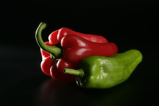 Red and green pepper over black background