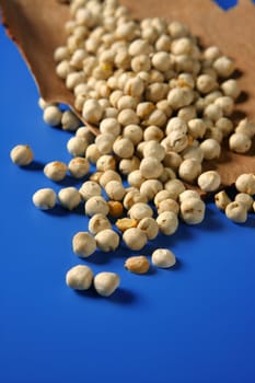 Chickpeas still spread over vivid blue background