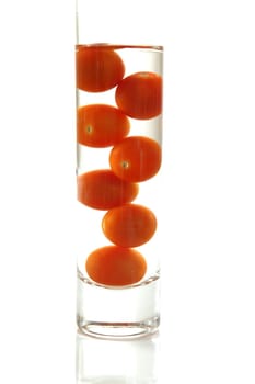 Cherry tomatoes in water glass over white