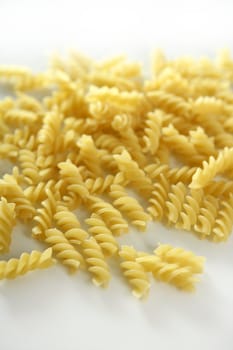 Italian spiral pasta texture with selective focus, white studio background