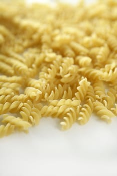 Italian spiral pasta texture with selective focus, white studio background