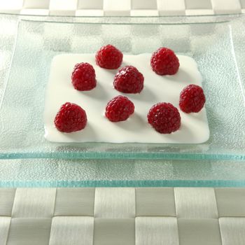 Dessert plate with cream and raspberries in square glass dish