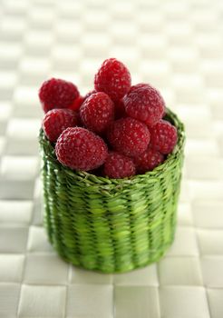 A group of fresh raspberries in a green little basket