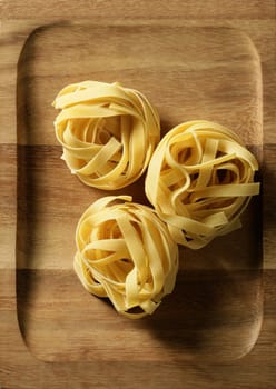 Dried macro noodles yellow pasta, studio shot texture over oriental warm wood plate