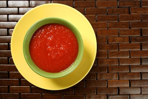 Tomato soup in colorful green dish over wood