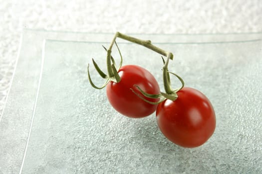 Two cherry tomatoes close-up in a square transparent plate