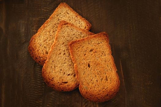 Toasted bread slices over old dark wood background