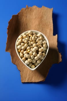 Chickpeas in a bowl over wood and blue background