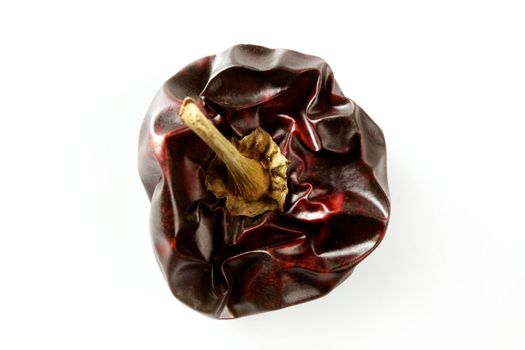 One round Mediterranean dried dark red peppers over white at studio, isolated