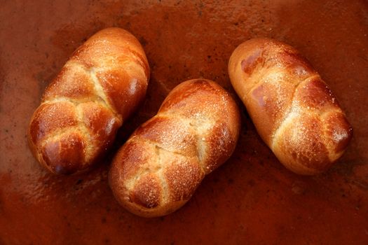 Three brioche pastries over orange brown clay background, bakery