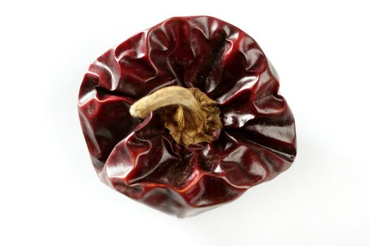 One round Mediterranean dried dark red peppers over white at studio, isolated