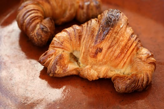 Two croissant pastries over orange brown clay background