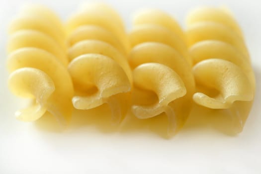 Spiral fusilli dired pasta macro over white studio background