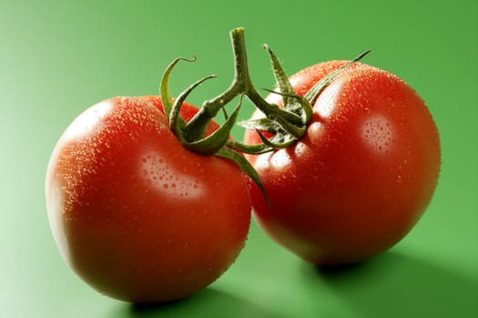 Red wet tomato macro over green background at studio