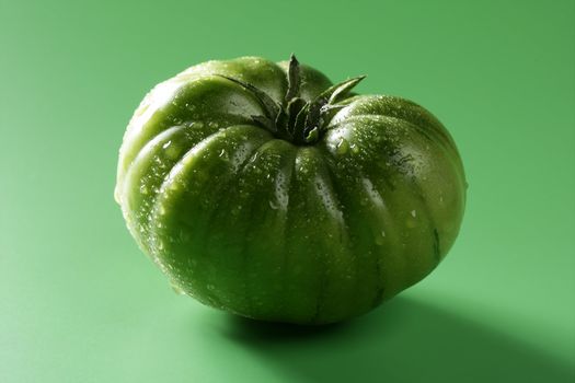 One green macro tomato, wet skin, studio shot