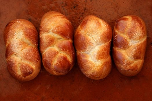 Four brioche pastries in a row, orange brown clay background, bakery