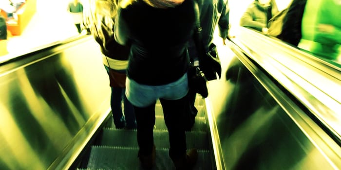 People going down the escalator (motion blur, high key)