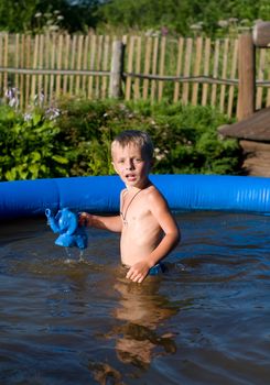 The boy plays the inflatable pool established on a country site.