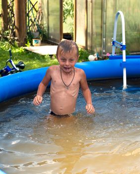 The boy bathes in dark blue inflatable pool