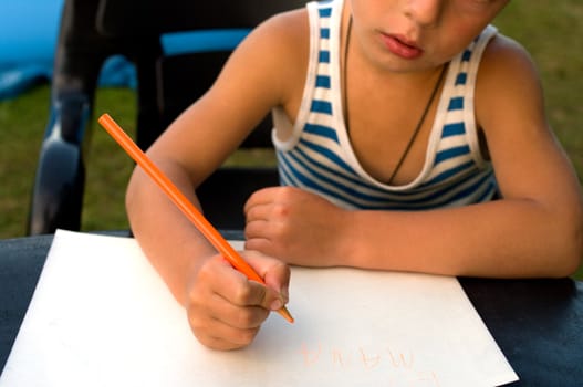 The little boy studies to write a word mama.