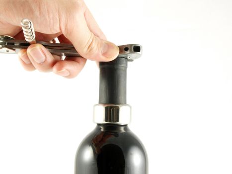 Someone opening a wine bottle, cutting off the top cover, towards white