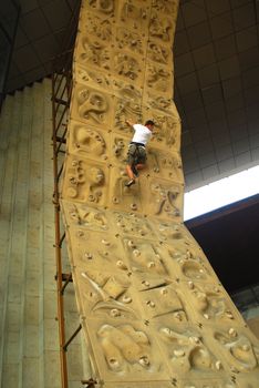 upward view of person climbing up a climbing wall
