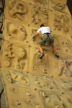 upward view of person climbing up a climbing wall
