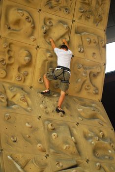 upward view of person climbing up a climbing wall
