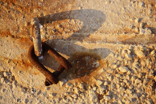 old rusted shackle on the harbor concrete stones, golden sunset light