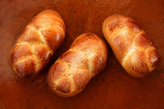 Three brioche pastries over orange brown clay background, bakery