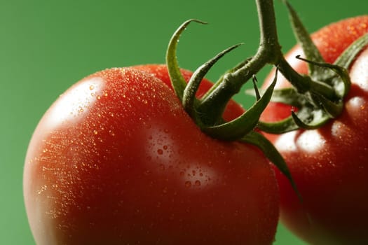 Red wet tomato macro over green background at studio