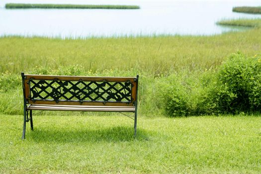 Bench over the green grass on the lake, peace metaphor