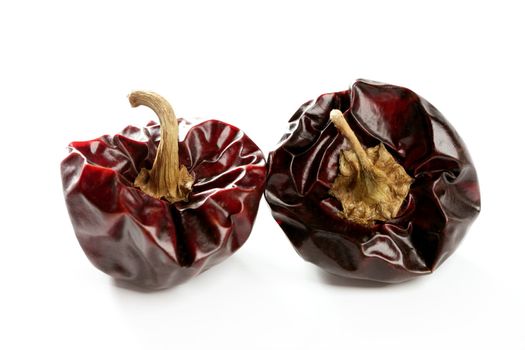 Two round Mediterranean dried dark red peppers over white at studio, isolated