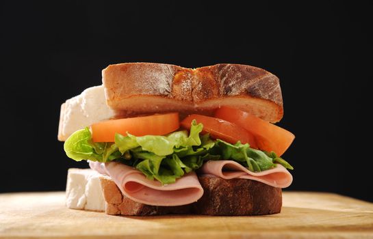 Ham, Lettuce and tomato sandwich made with thick white bread, shot on a wooden table.