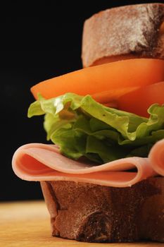 Ham, Lettuce and tomato sandwich made with thick white bread, shot on a wooden table.