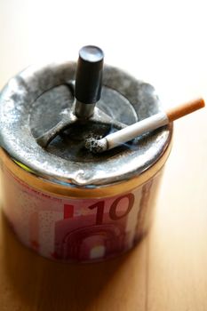 Ashtray with ten euro note decoration and cigarette