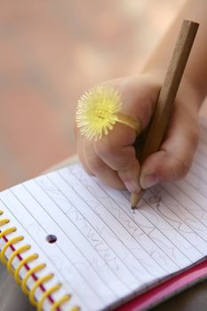 Children hand with funny finger yellow ring writing on a notebook