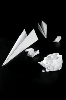 Trash paper and air plane, bored in the office metaphor, over black