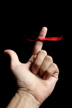 Red tape ribbon, loop tape around human finger over black background