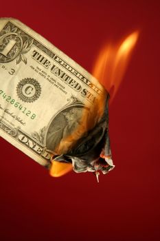 Dollar note, american currency burning in fire over red background, studio shot