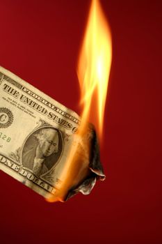 Dollar note, american currency burning in fire over red background, studio shot