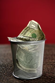 Dollar bank notes on the trash over brown tablecloth, red background