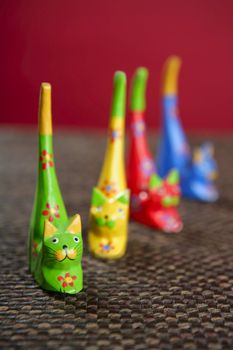 four handcraft cats in colors still over brown tablecloth