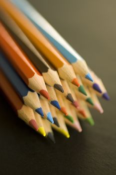 Close up of group of multi-colored coloring pencils isolated on blsck background.