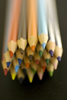 Close up of group of multi-colored coloring pencils isolated on blsck background.