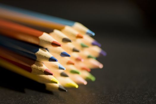 Close up of group of multi-colored coloring pencils isolated on blsck background.