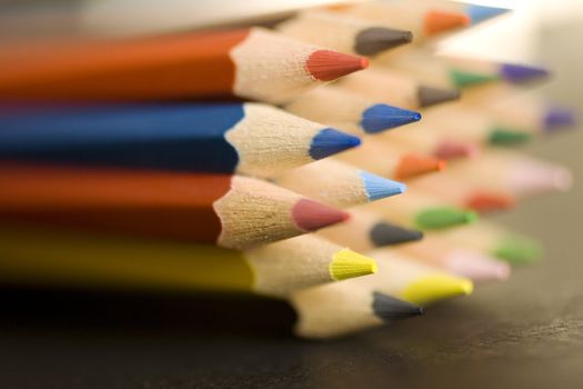 Close up of group of multi-colored coloring pencils isolated on blsck background.