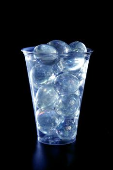 Glass balls under blue light in a plastic glass, black background
