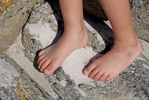 child feets on rock near the beach