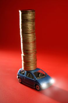 Business metaphor, toy car with huge column of golden coins over red